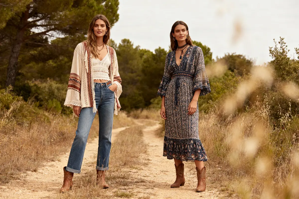 Deux femmes posent dans un chemin forestier, portant des vêtements bohémiens et bottes camel.
