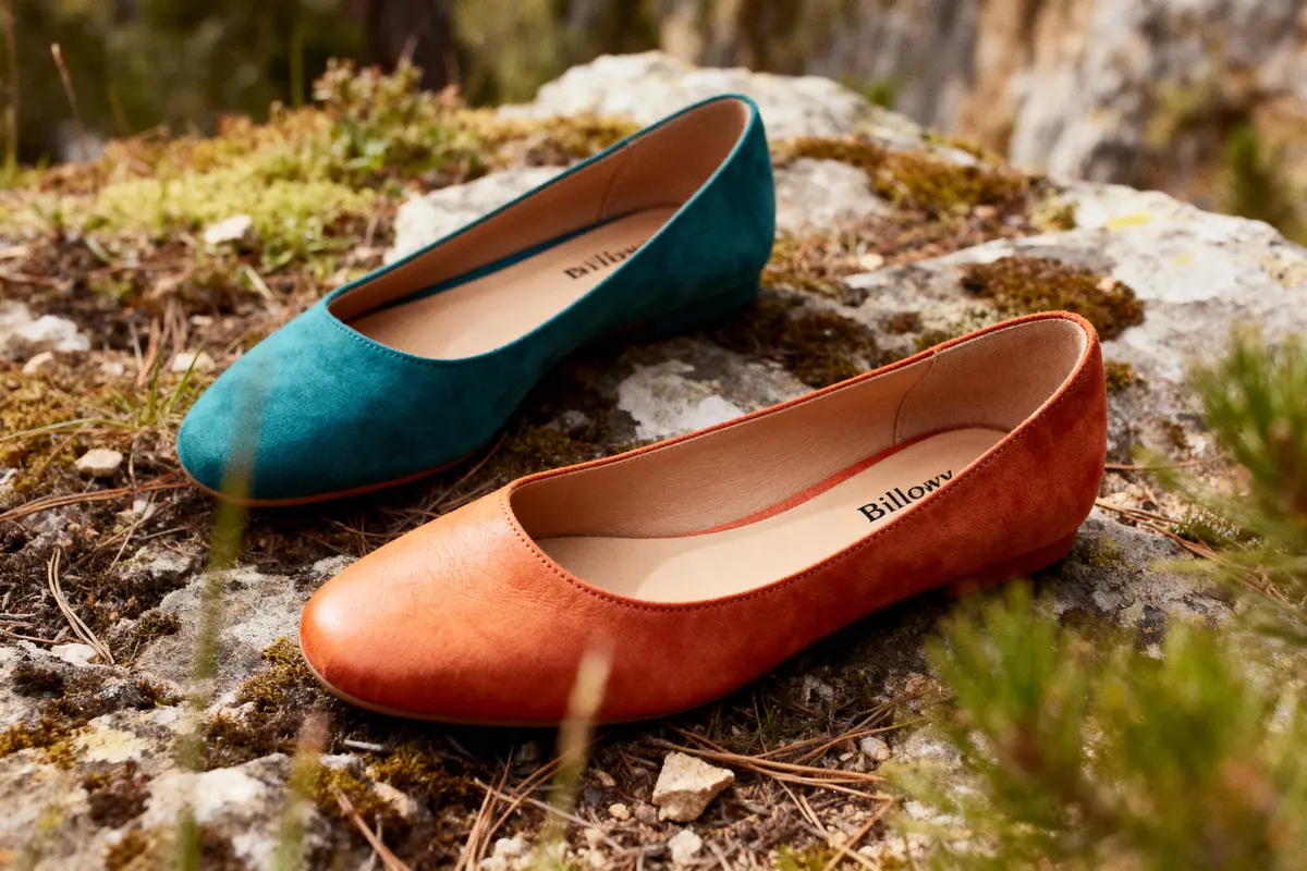 Deux ballerines, une turquoise et une orange, posées sur un sol rocheux et moussu en extérieur.