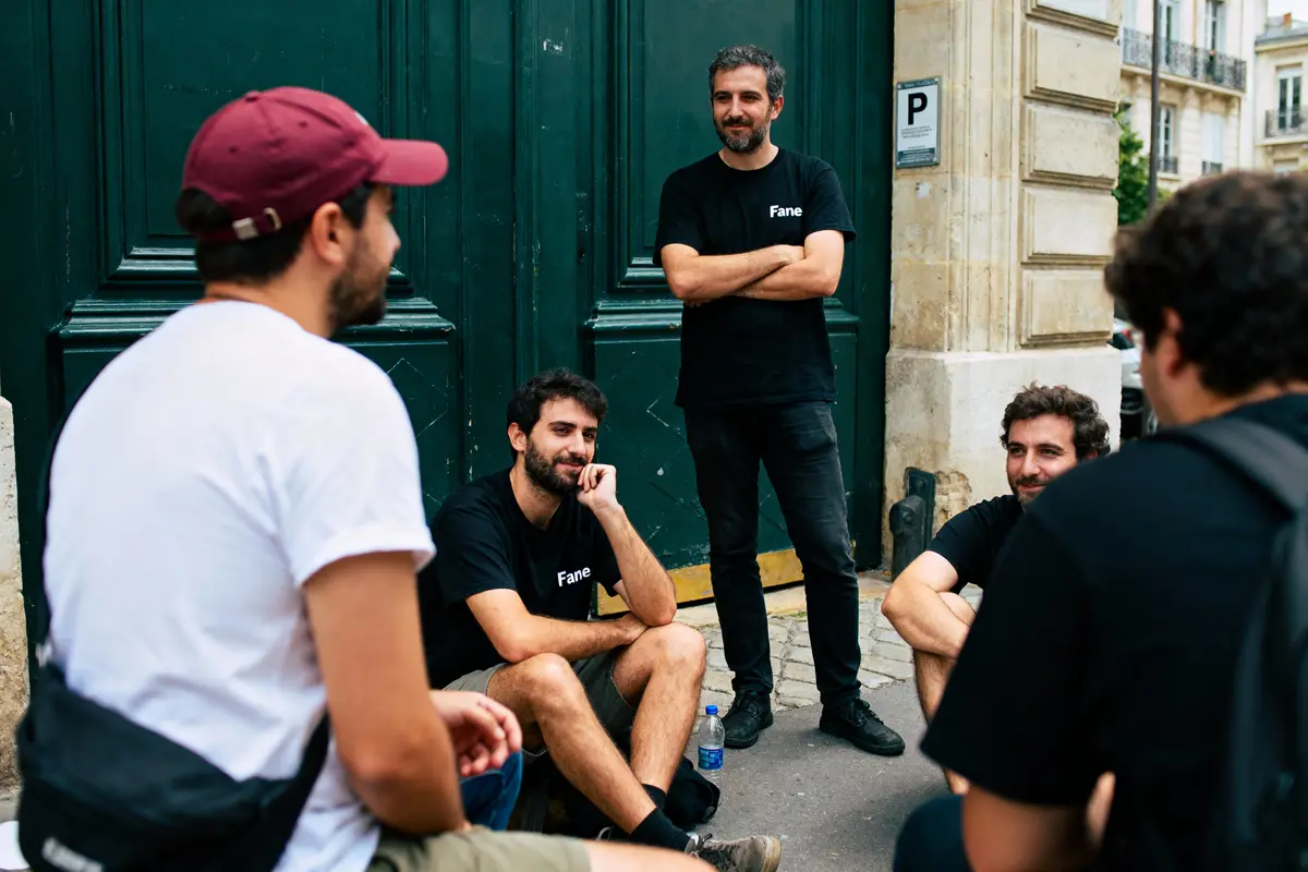 Un groupe de cinq hommes discute assis et debout devant une porte verte.