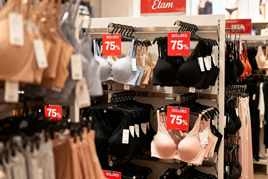 Magasin de lingerie Etam avec soutiens-gorge en solde à 75% de réduction affichés sur des panneaux rouges.