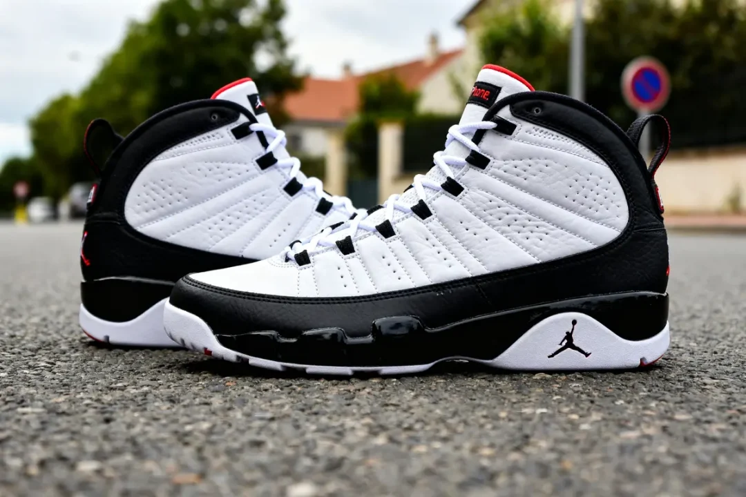Paire de sneakers Jordan 9 noires et blanches sur une route en extérieur