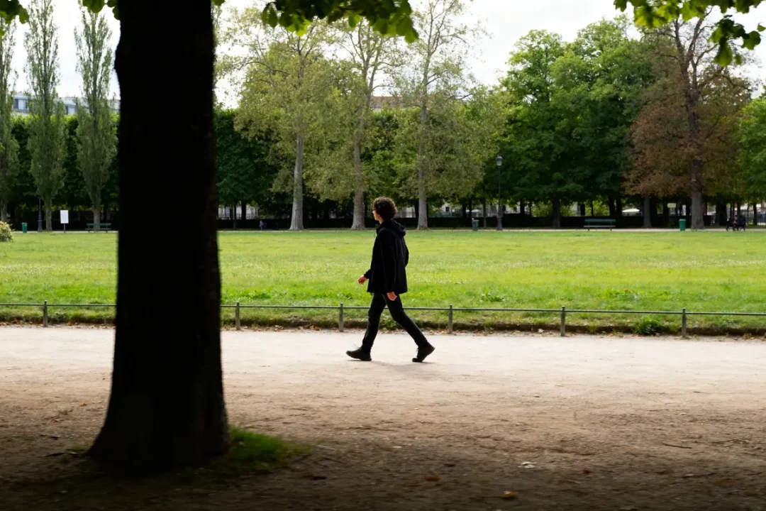 Personne marchant dans un parc, illustrant le parcours de 13000 pas en kilomètres