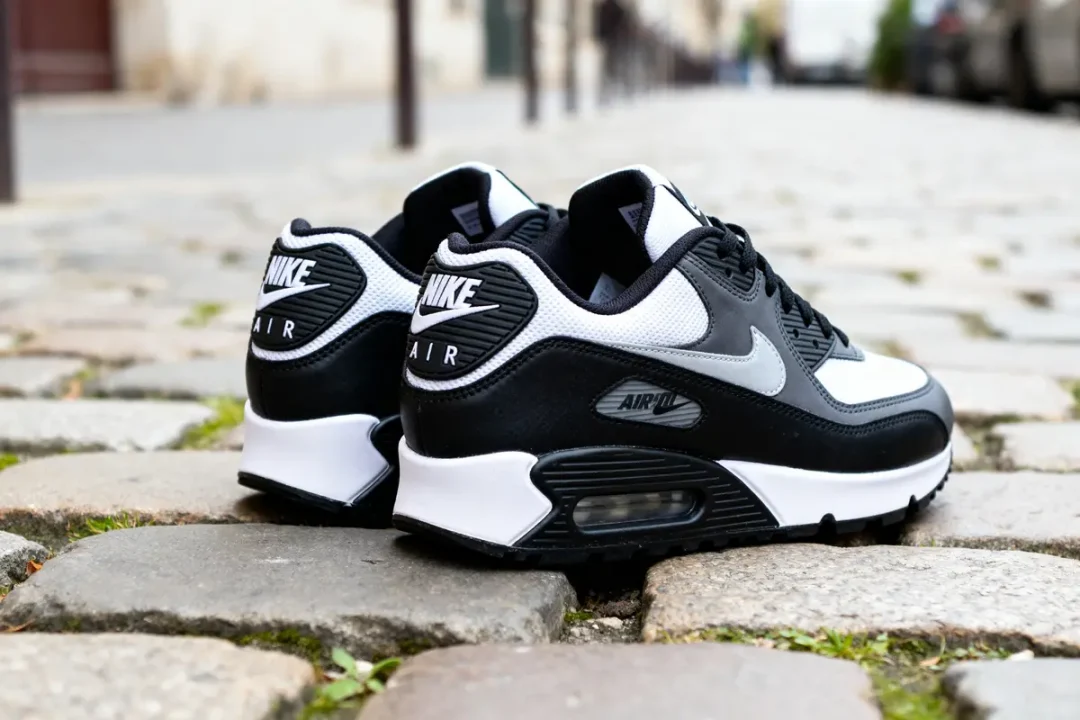 Chaussures Air Max noir blanc sur pavés urbains, vue arrière détaillée