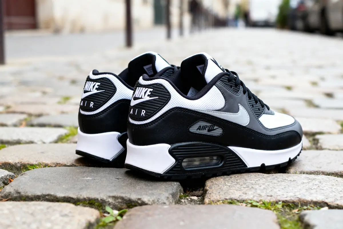 Chaussures Air Max noir blanc sur pavés urbains, vue arrière détaillée