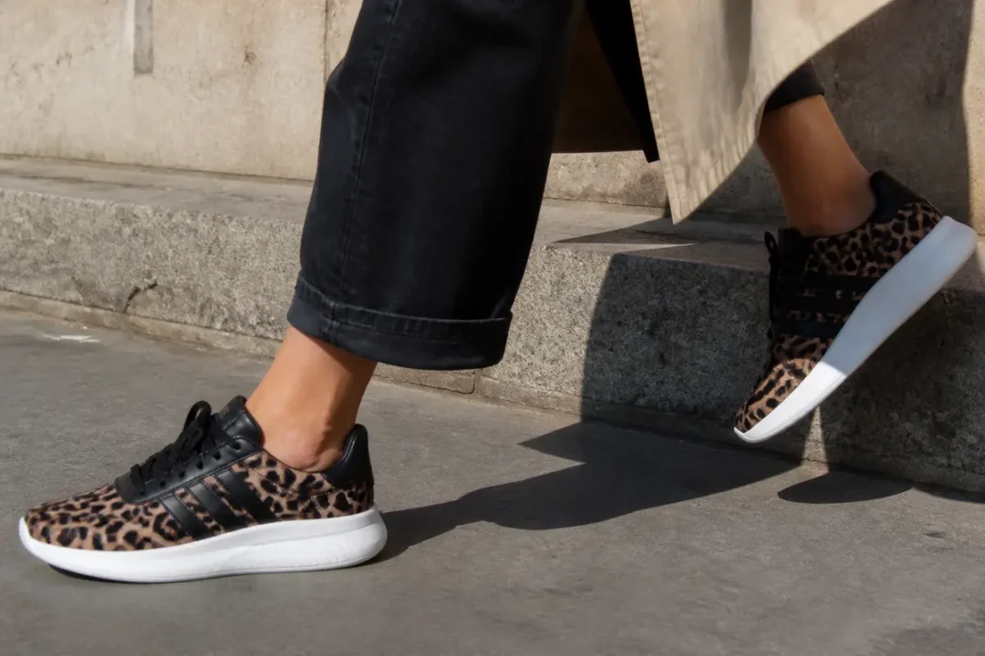 Femme portant des baskets Adidas léopard pour femme montant des marches grises en extérieur