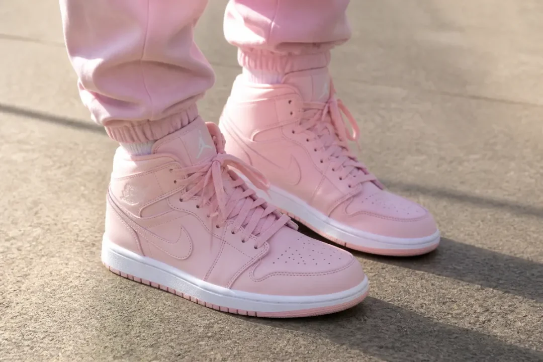 Chaussures Jordan en rose pastel avec pantalon assorti sur fond gris clair.